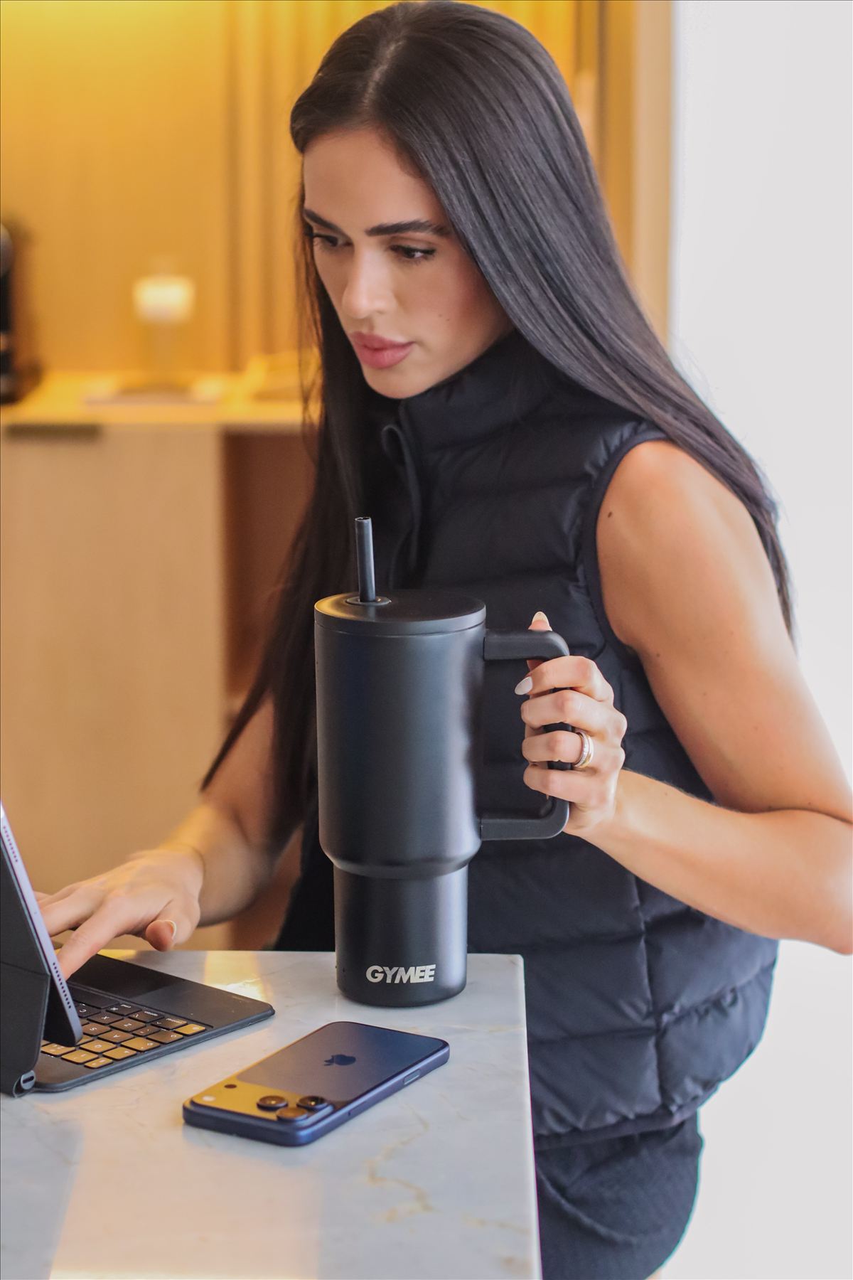 Mulher com caneca térmica GYMEE preta durante home office