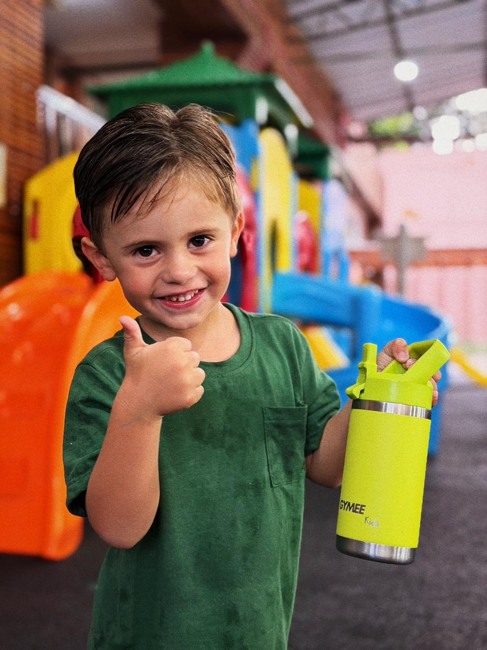 Menino sorrindo com garrafinha GYMEE Kids no parquinho da escola