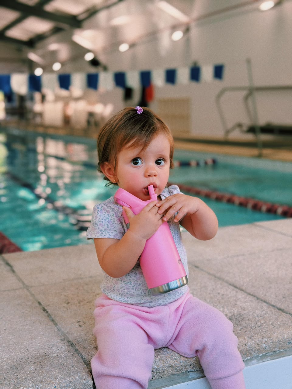 Criança com garrafinha GYMEE Kids rosa na beira da piscina da escola